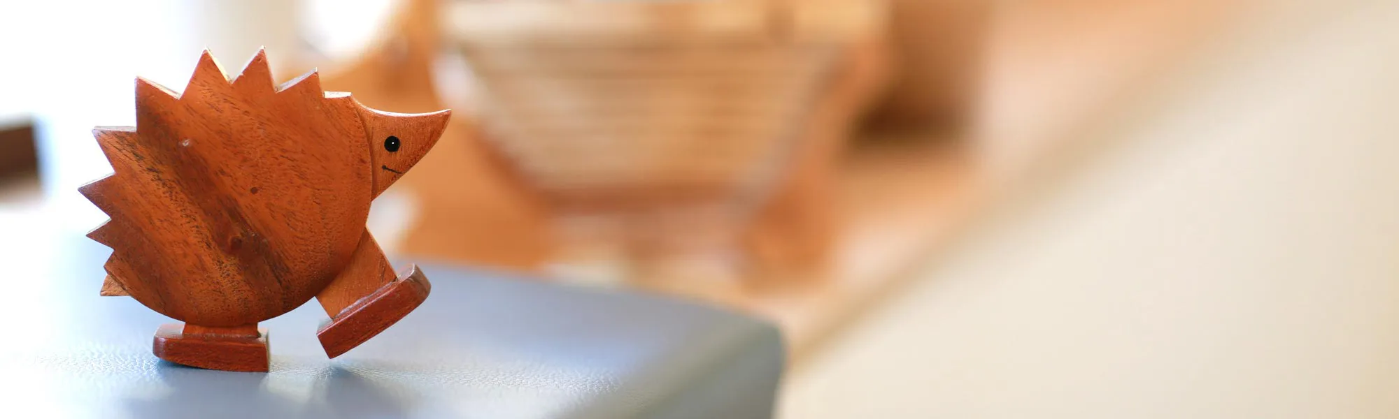 Kleine Holzfigur eines Igels auf Tisch mit warmem Hintergrund